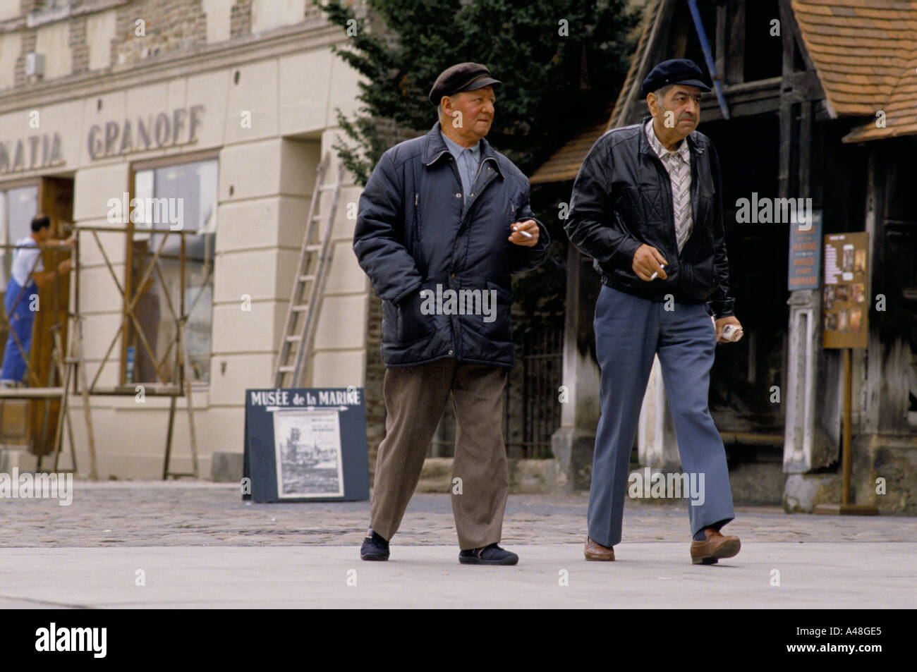 Two men walking through the Town Centre in Honfleur Normandy Stock Photo