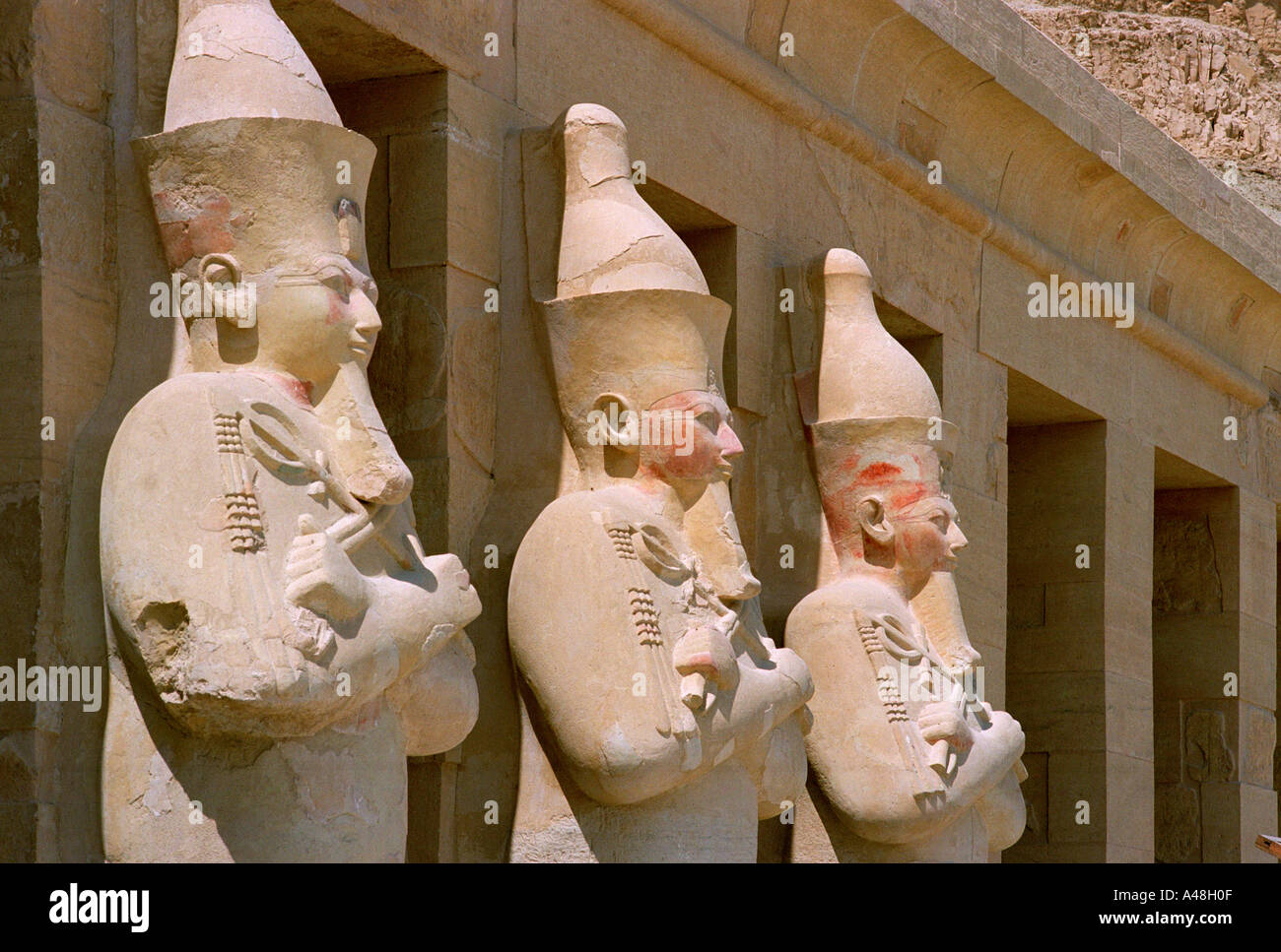 Statues of pharoahs stand in imperious majesty overlooking the entrance causeway to the temple of Queen Hatshepsut near Luxor Stock Photo