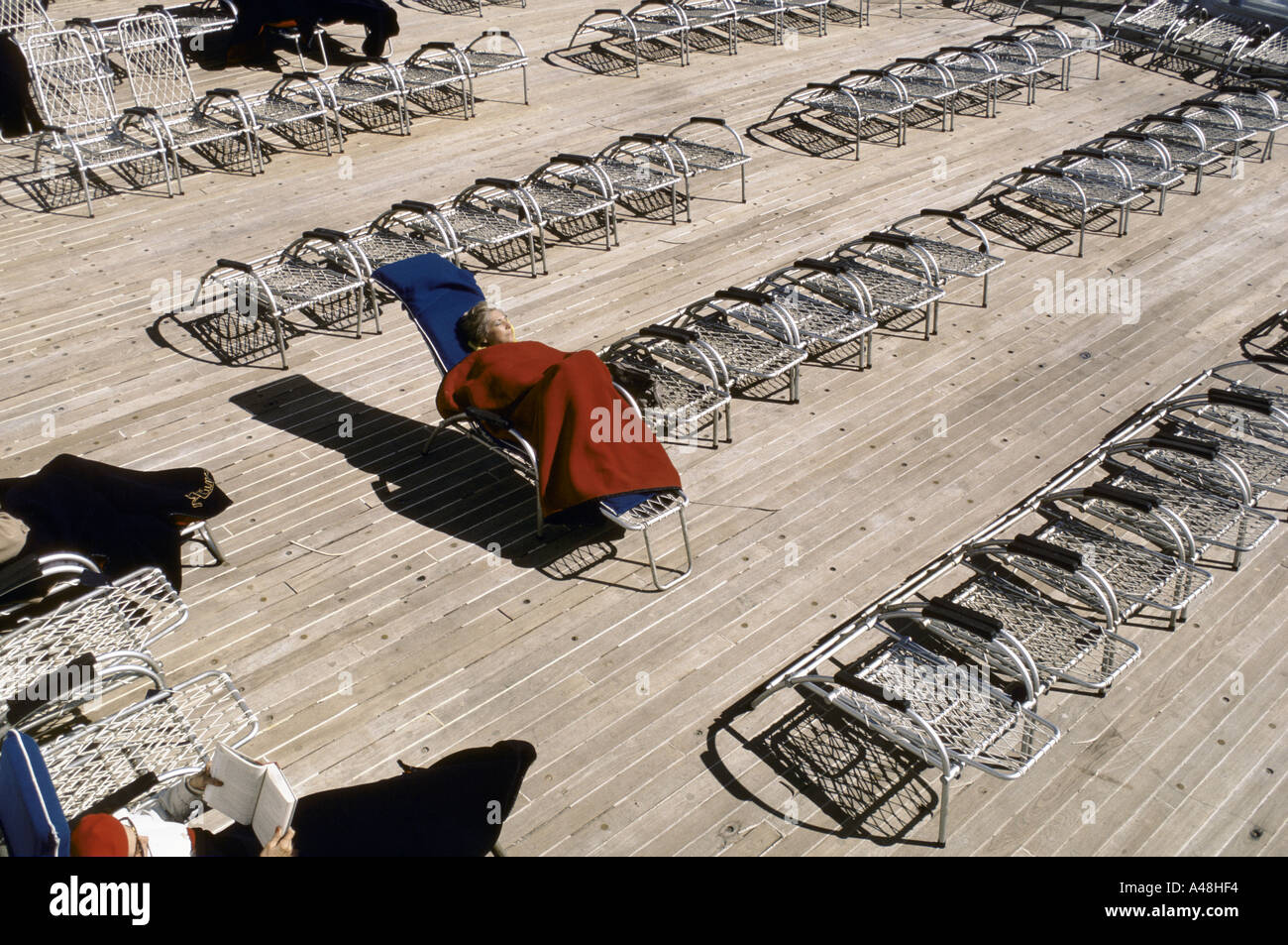 woman lying on reclining chair keeping warm underneath a blanket on the
