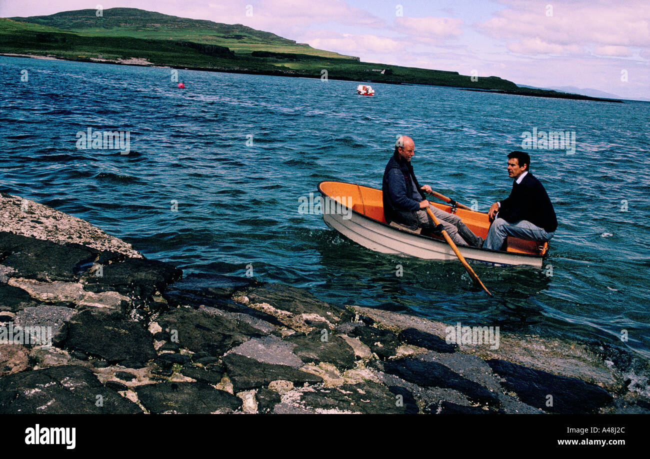 The postman rowing his dinghy to eigg  after collecting the mail from the mail boat, isle of eigg Stock Photo