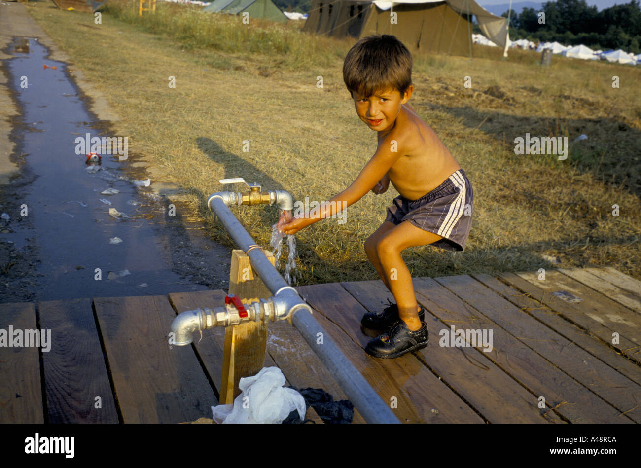 child refugee from srebrenica in tuzla july 1995 washing at  stand pipe. Tuzla aerodrome Stock Photo