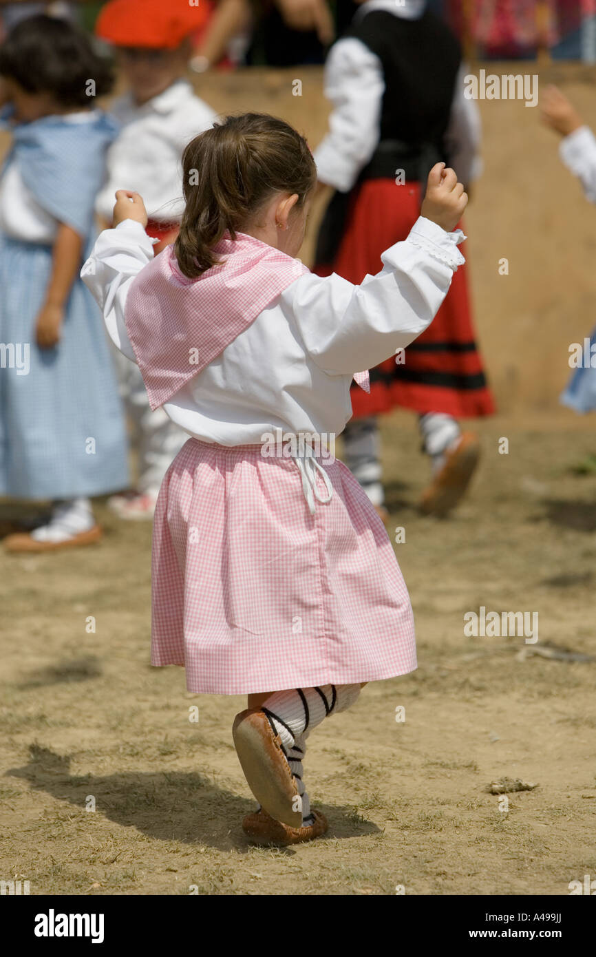 Very young Basque girl in pink dress performing traditional folk dance ...