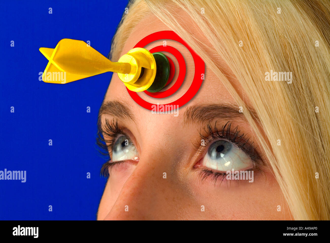 Dart on forehead of a young blond girl with target between her eyes