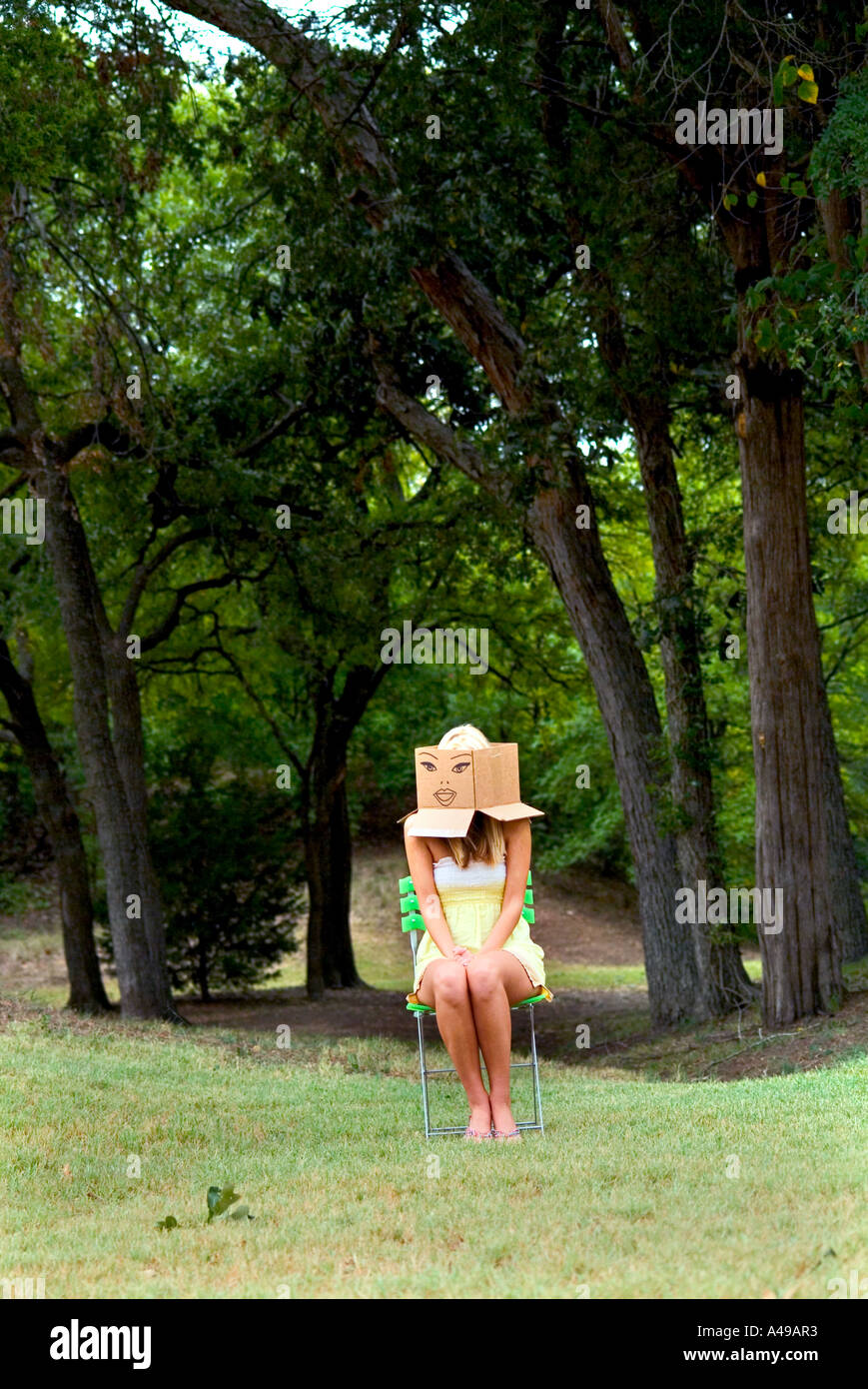 Woman wearing a cardboard box on head with cartoon face drawn on it Stock Photo