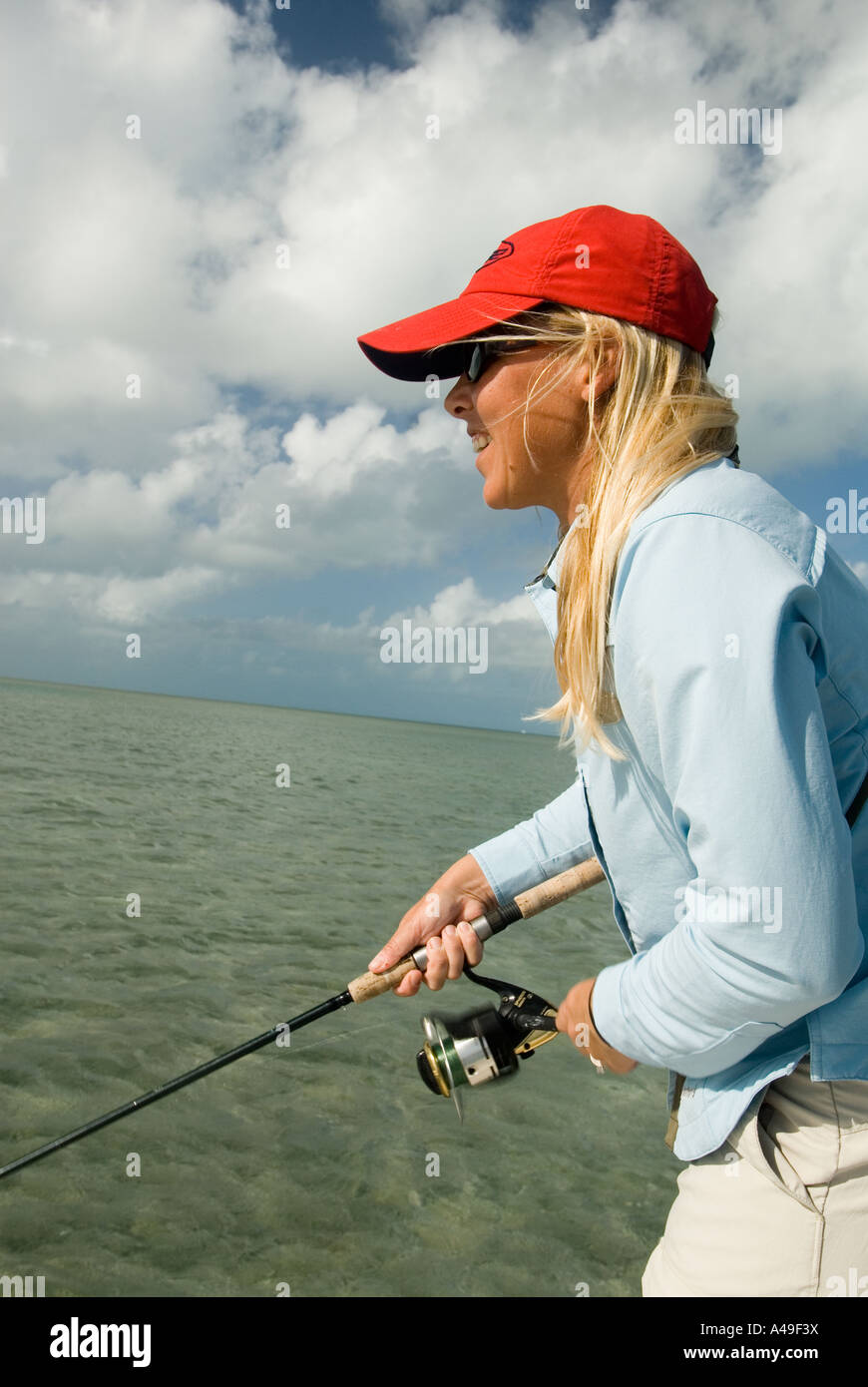 USA Florida Keys Woman fisherman in red hat fishing from flats
