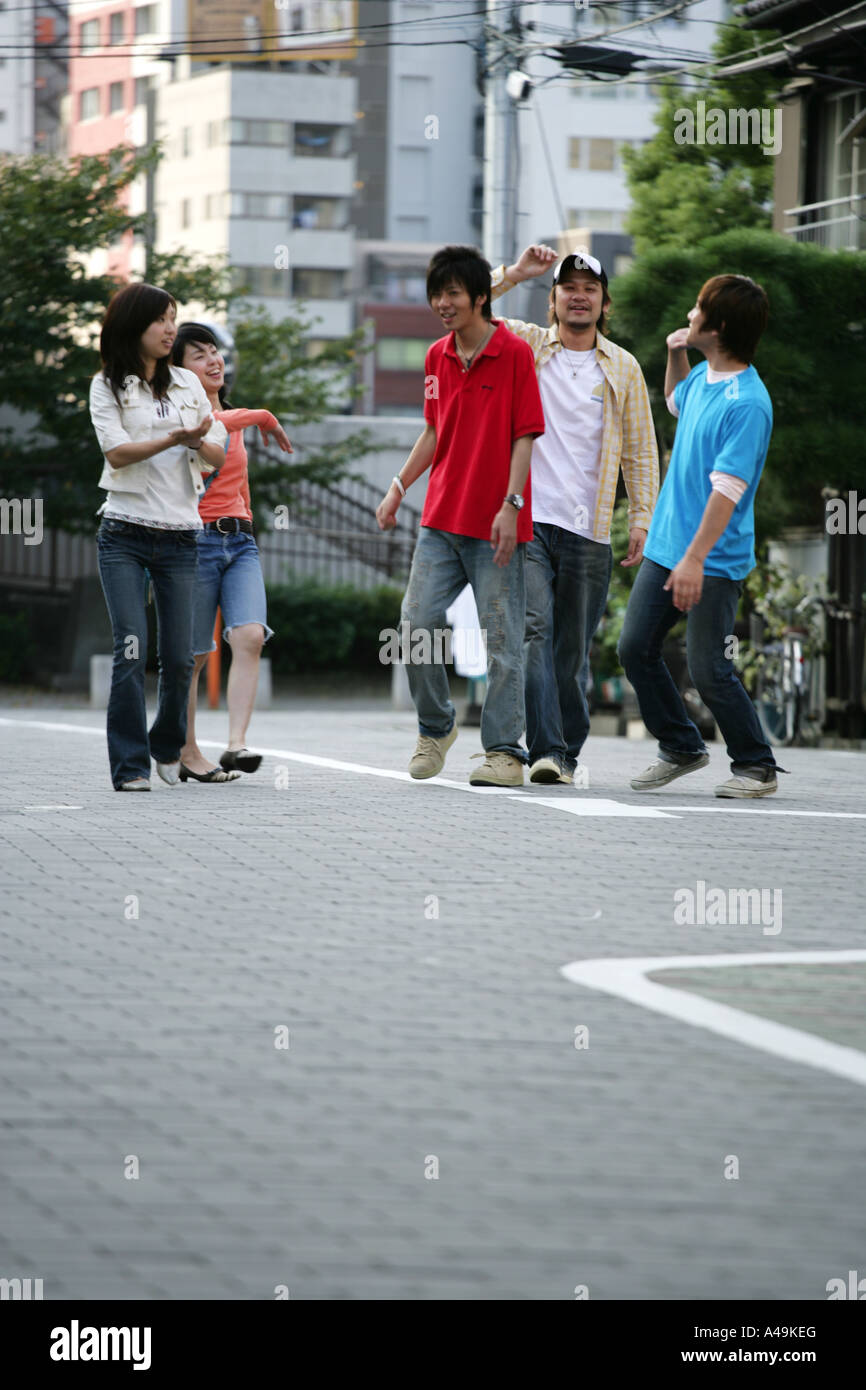 Three young men and two young women walking Stock Photo - Alamy