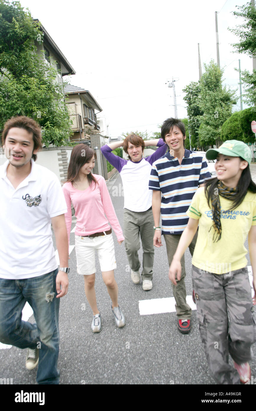Three young men and two young women walking Stock Photo - Alamy