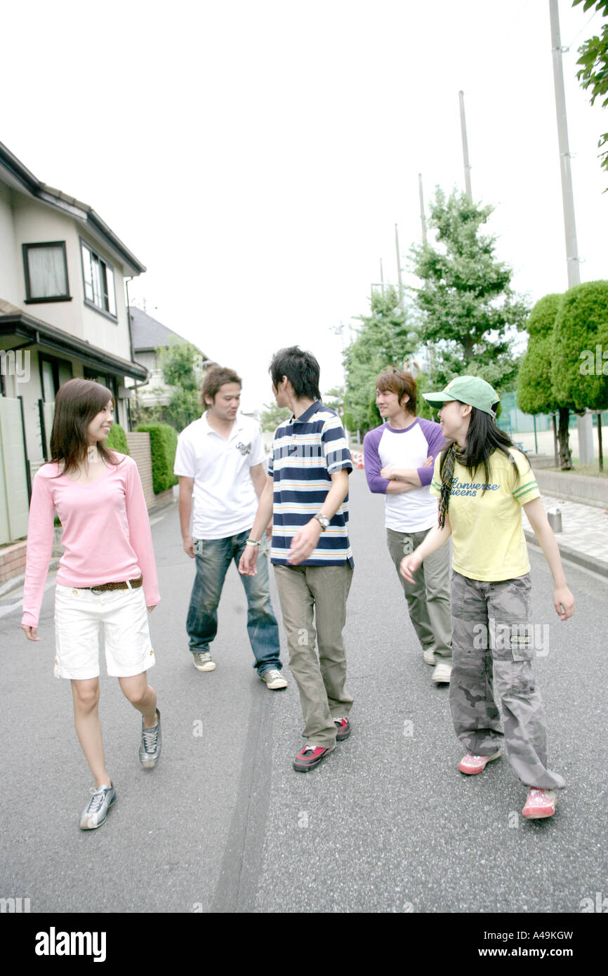 Three young men and two young women walking Stock Photo - Alamy