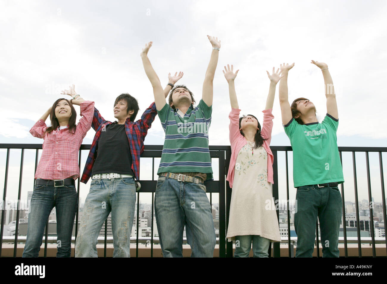 Three young men and two young women standing in front of a railing ...