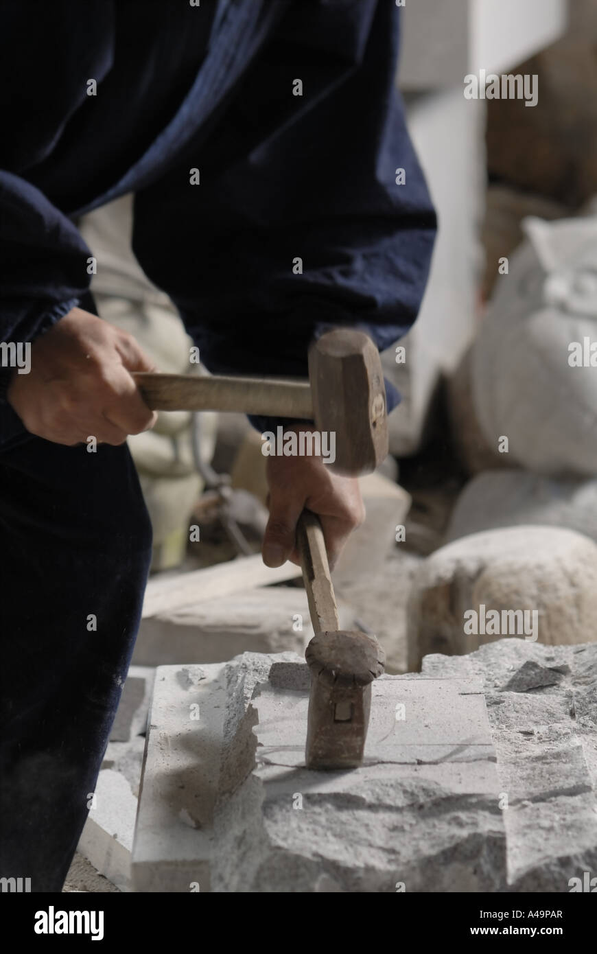 Mid section view of a sculptor carving stone with hammers Stock Photo
