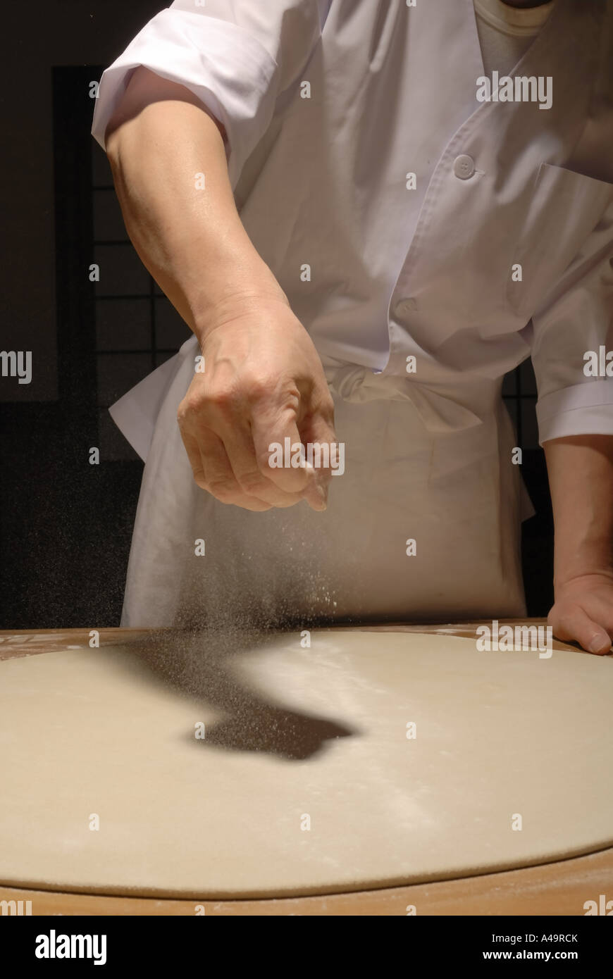 Mid section view of a chef spreading flour on rolled dough Stock Photo