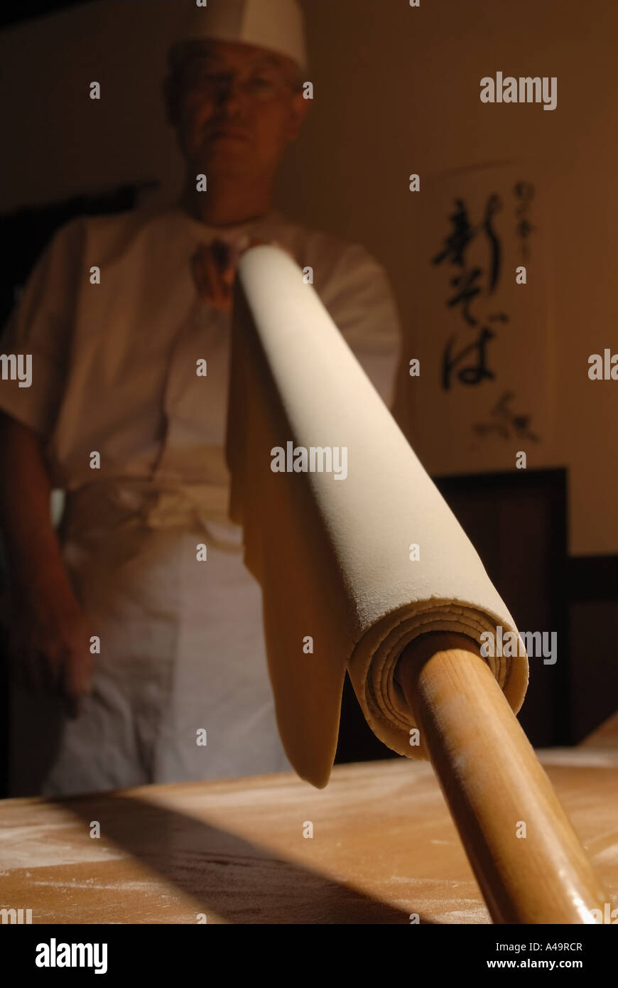 Chef holding a rolling pin with a rolled dough wrapped on it Stock Photo