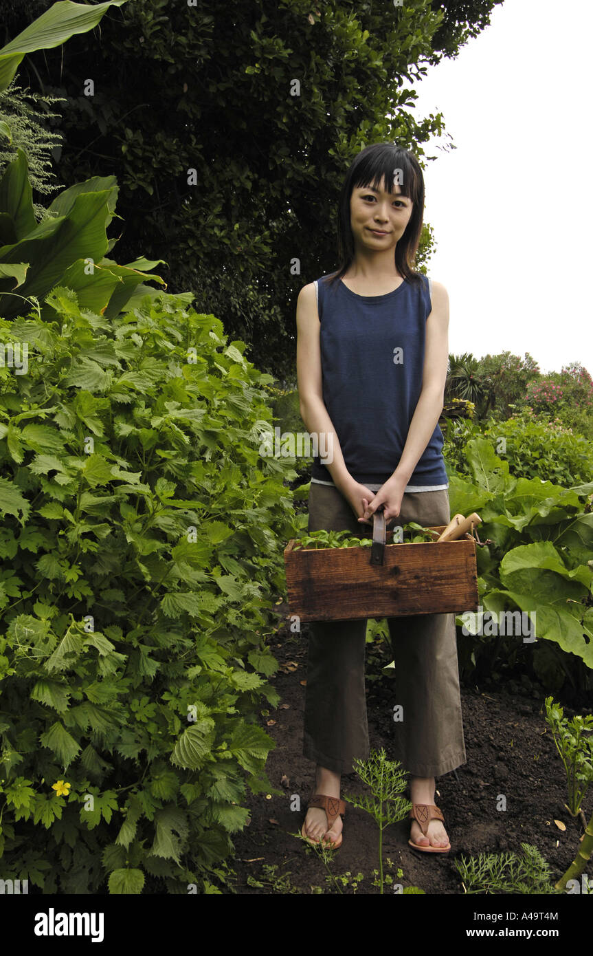 Portrait of a young woman holding a basket and standing in a garden ...