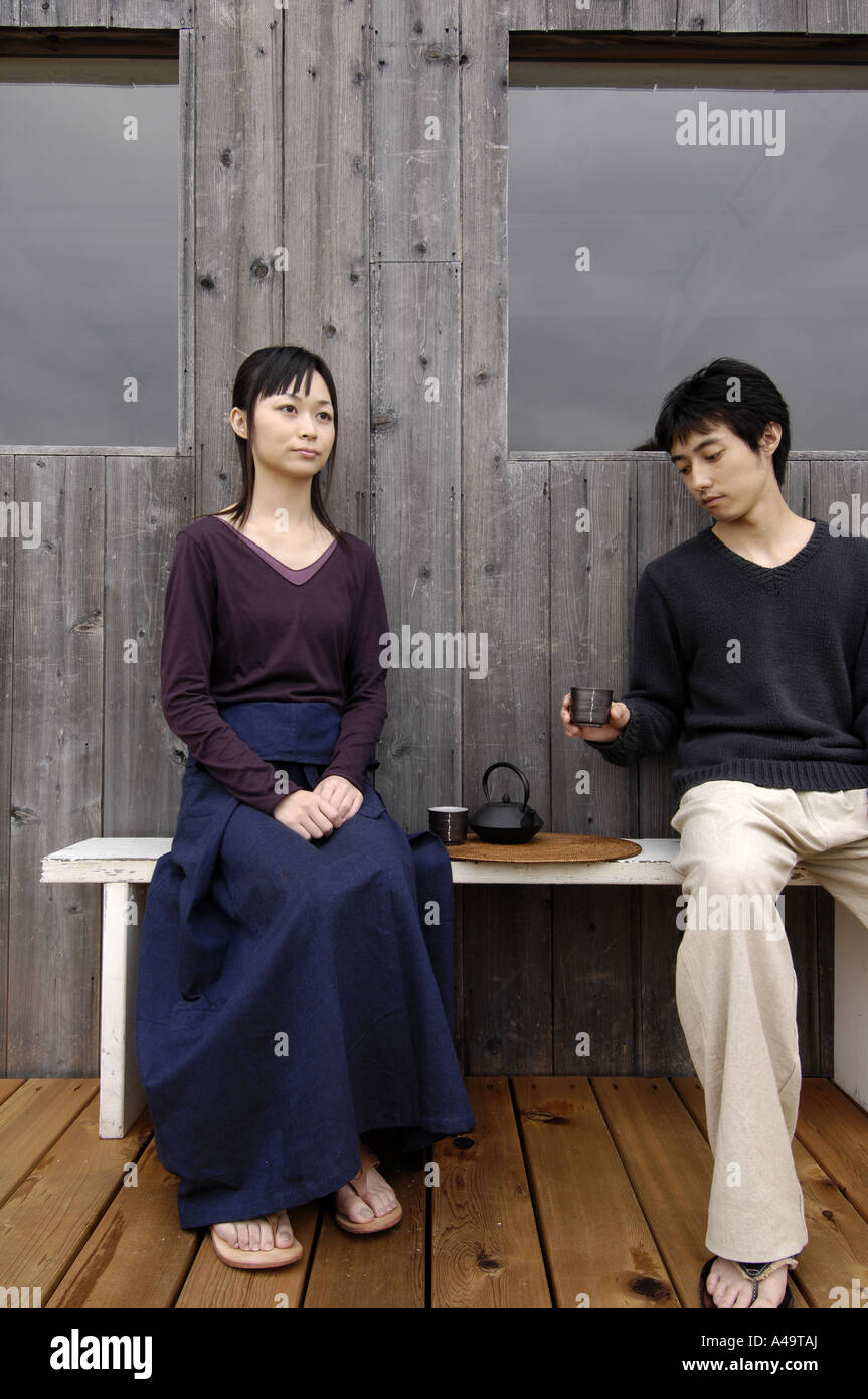 Young couple sitting on a bench Stock Photo - Alamy