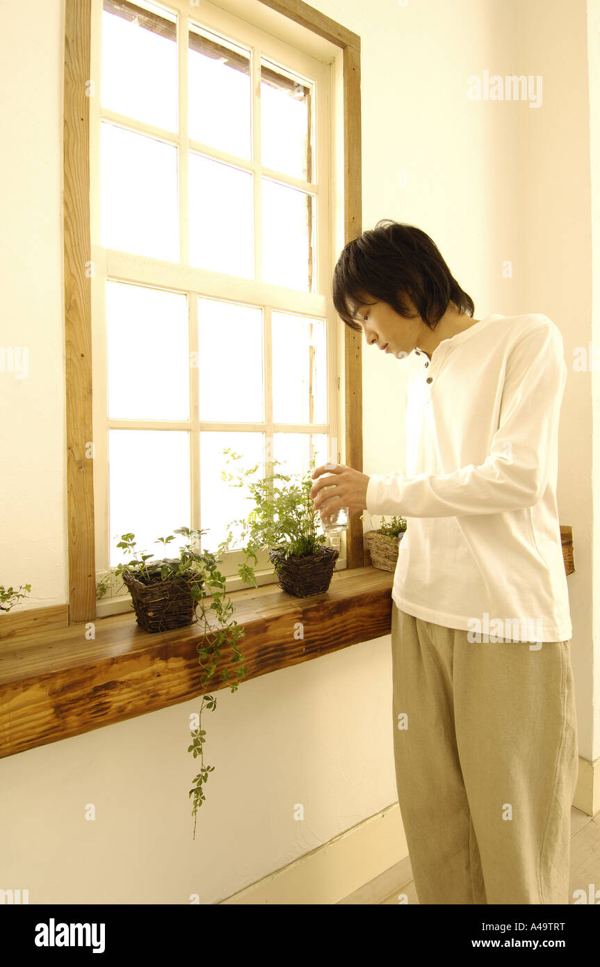 Young man watering a potted plant Stock Photo - Alamy