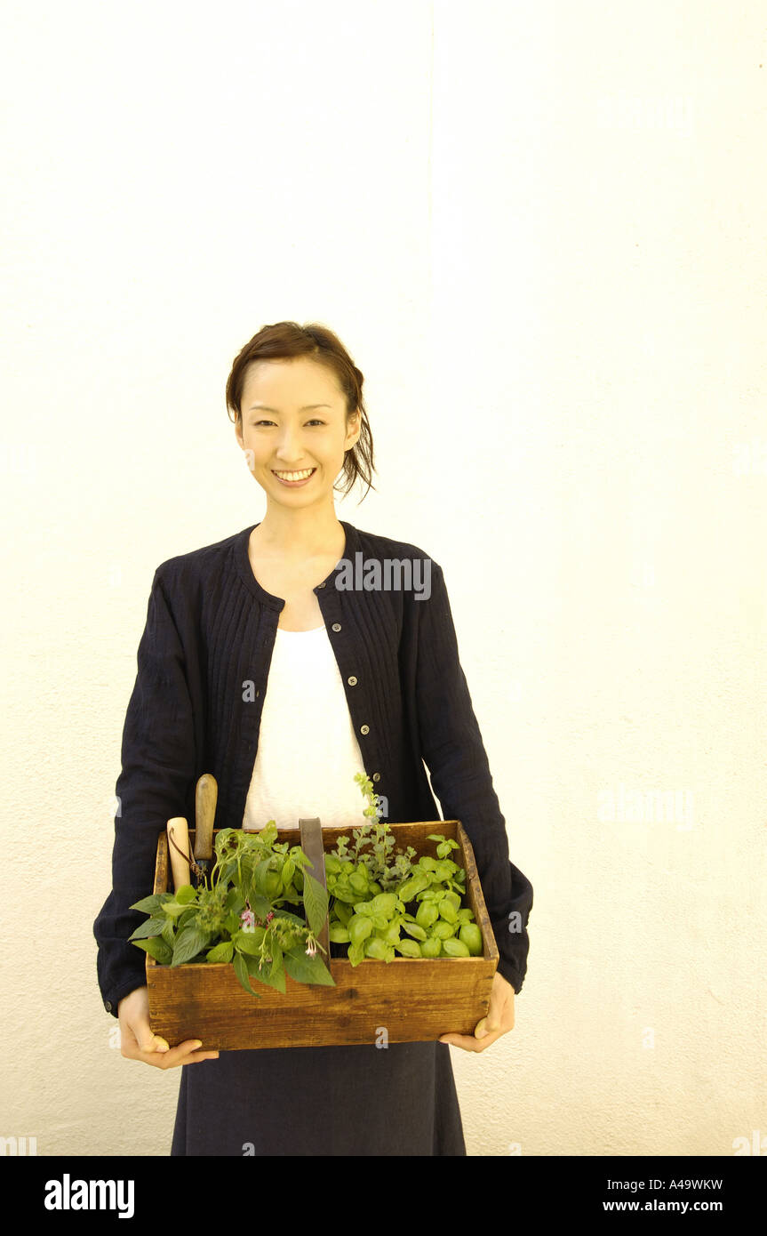 Portrait of a young woman holding a potted plant Stock Photo - Alamy