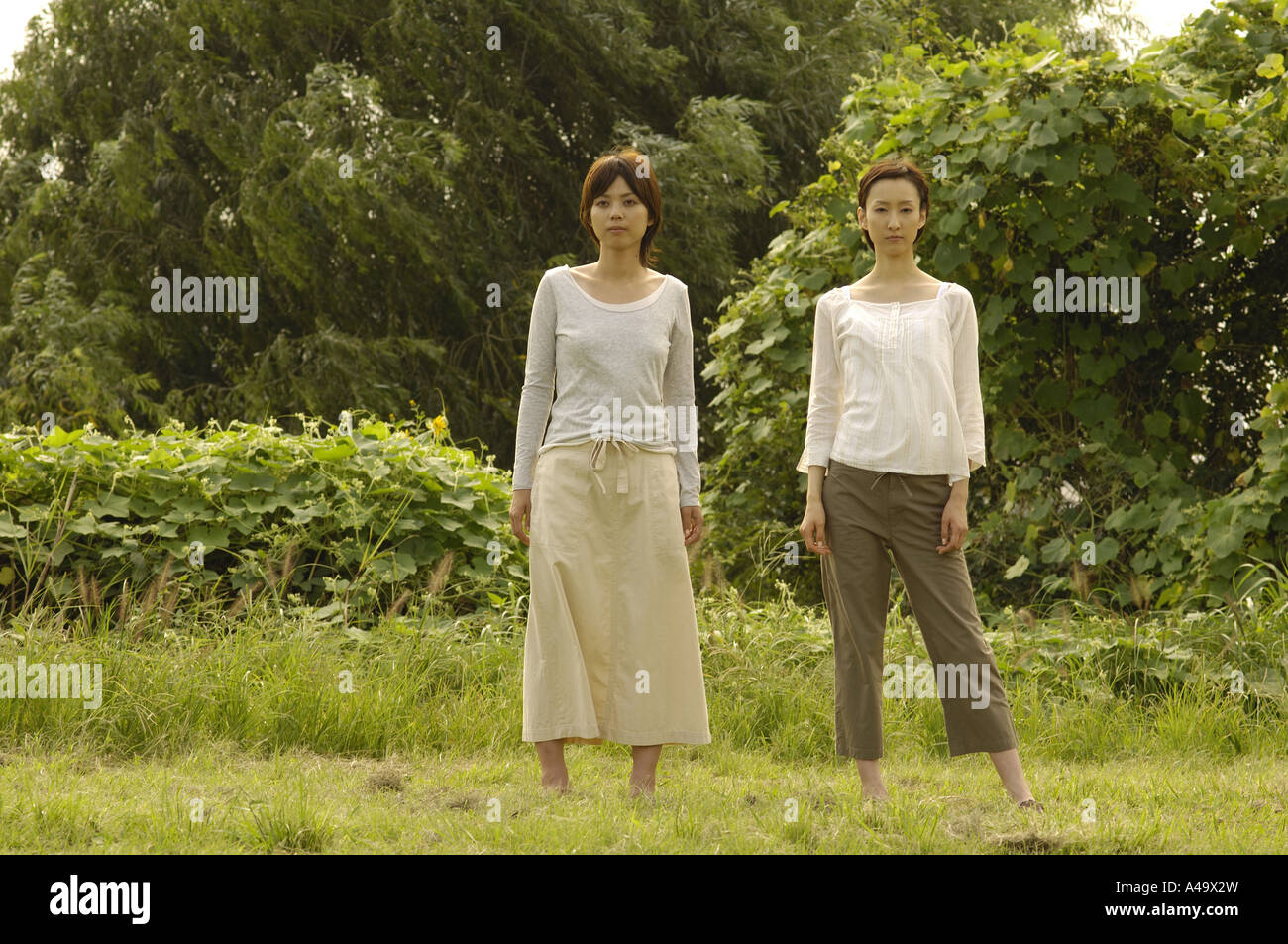 Portrait of two young women standing in a field Stock Photo - Alamy