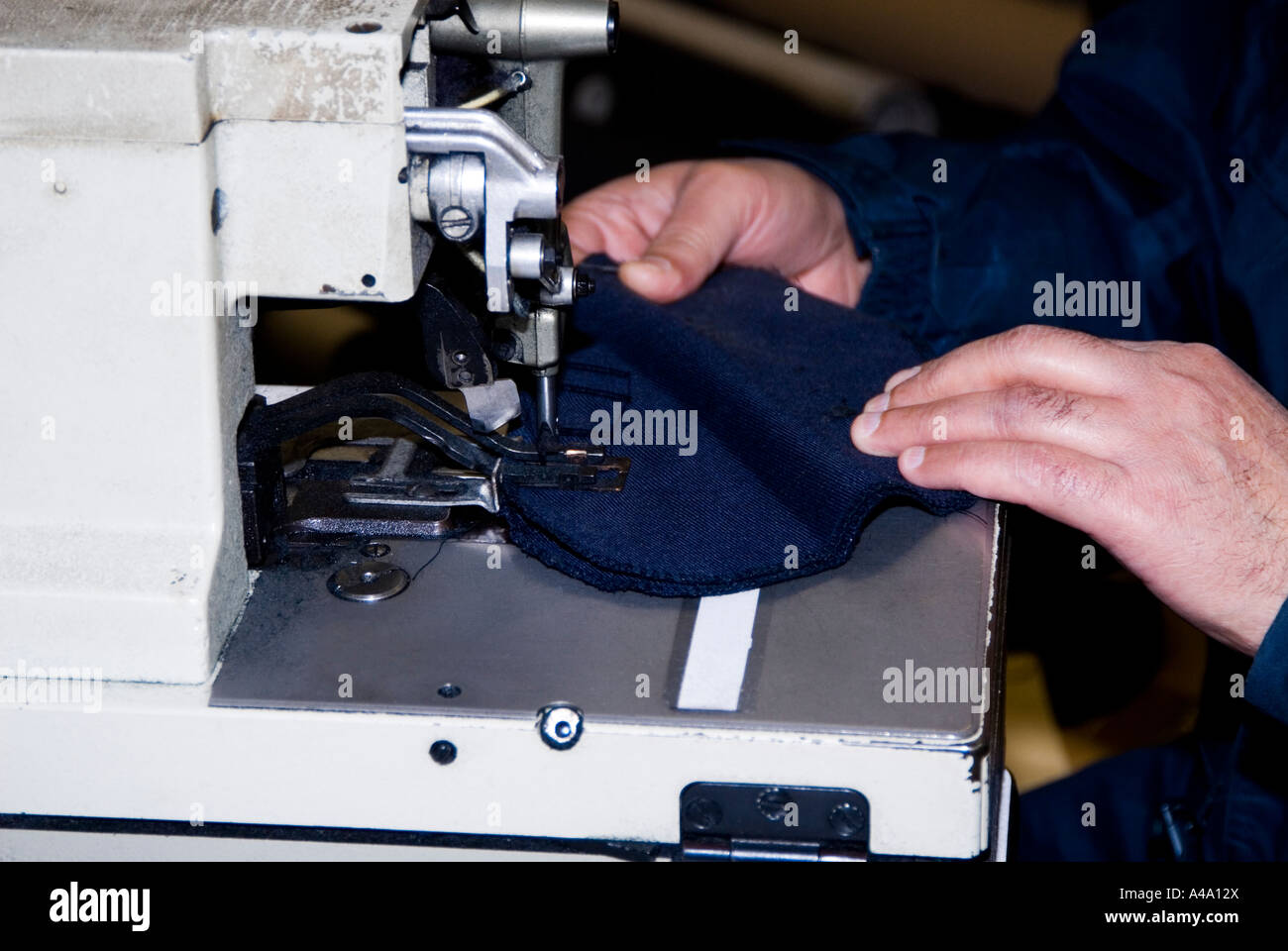 man operating on an Eyelet buttonhole machine Stock Photo