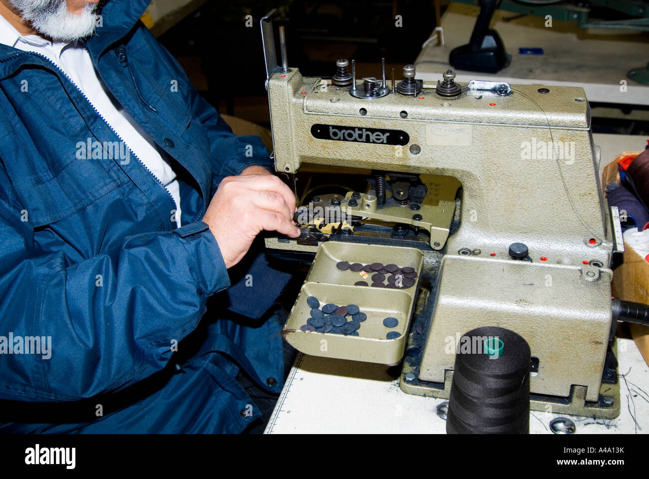 old man operating on Lockstitch Button machine Stock Photo