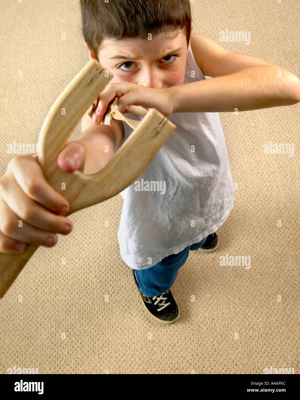 angry boy pointing slingshot at camera Stock Photo
