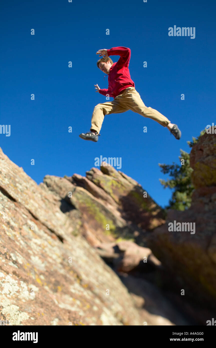 caucasian Man leaps across large distance while bouldering in Boulder Colorado Stock Photo