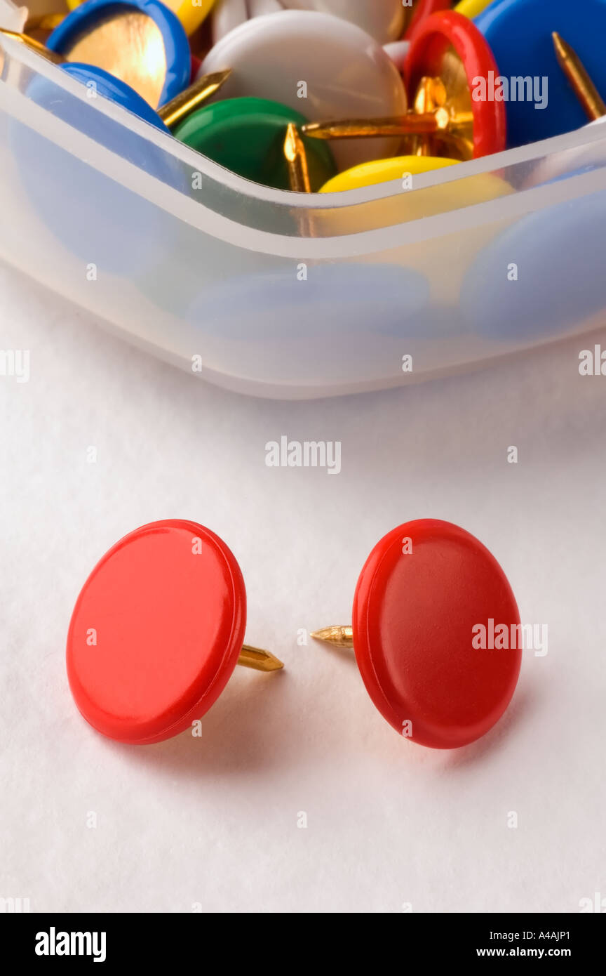 A close up of two red drawing pins  thumb tacks, with more of different colors in the background Stock Photo