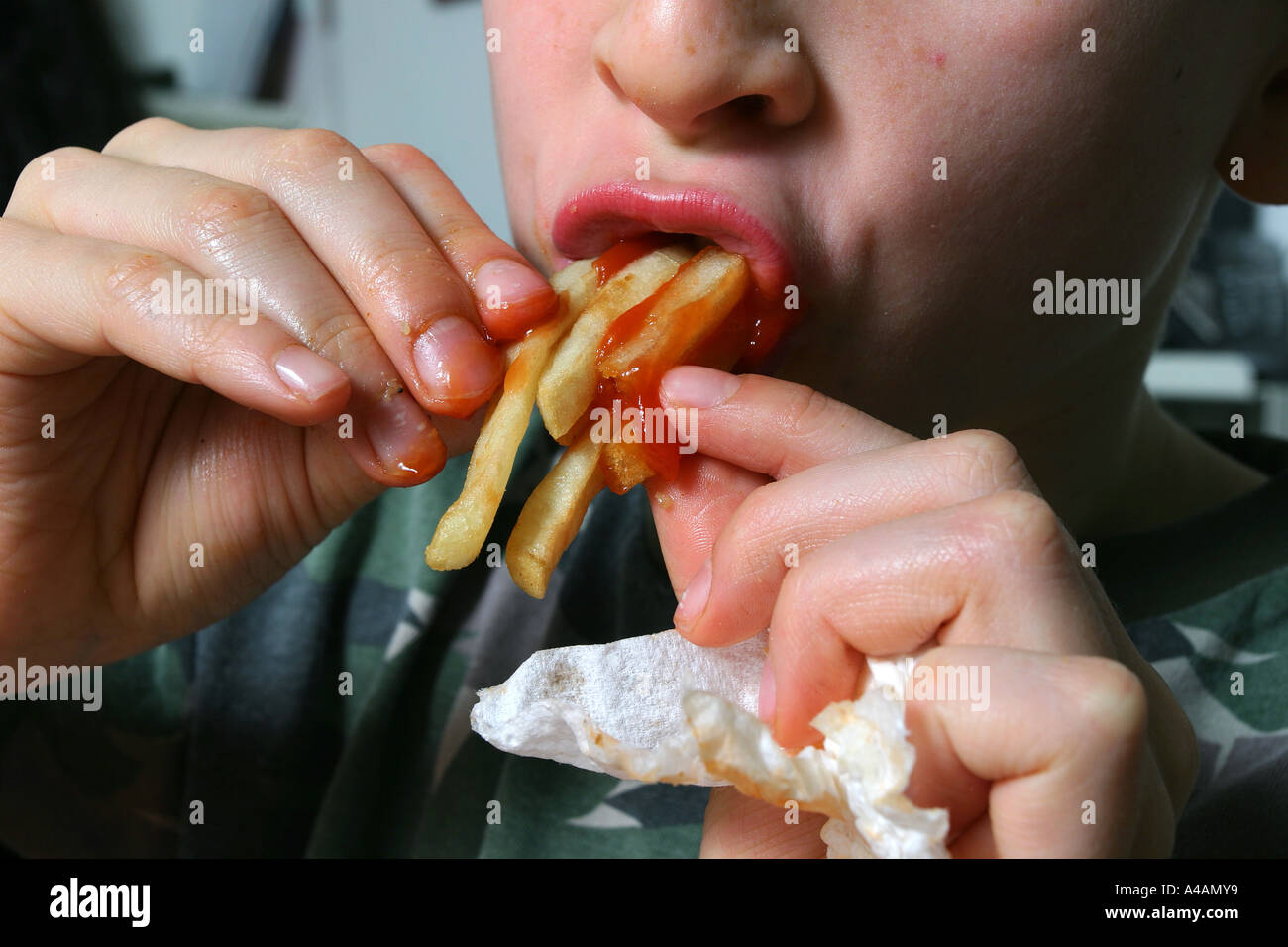 An eight year old boy eating chips covered in tomato ketchup, February