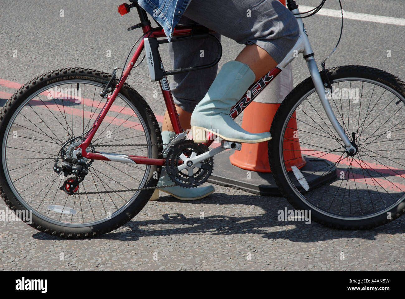 A woman rides a bike in cowboy boots Stock Photo - Alamy