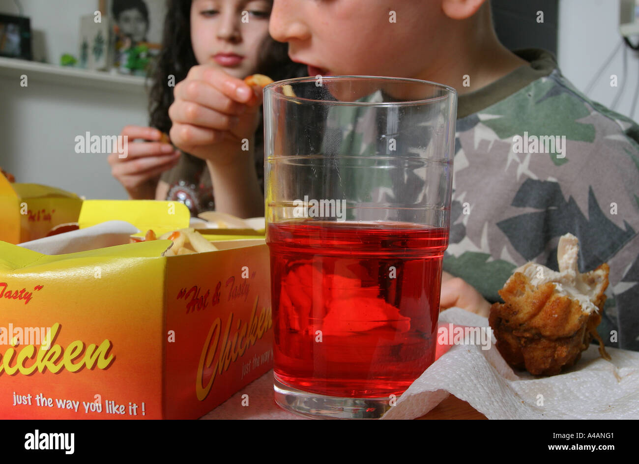 An eight year old boy eating a take away of fried chicken, chips and a