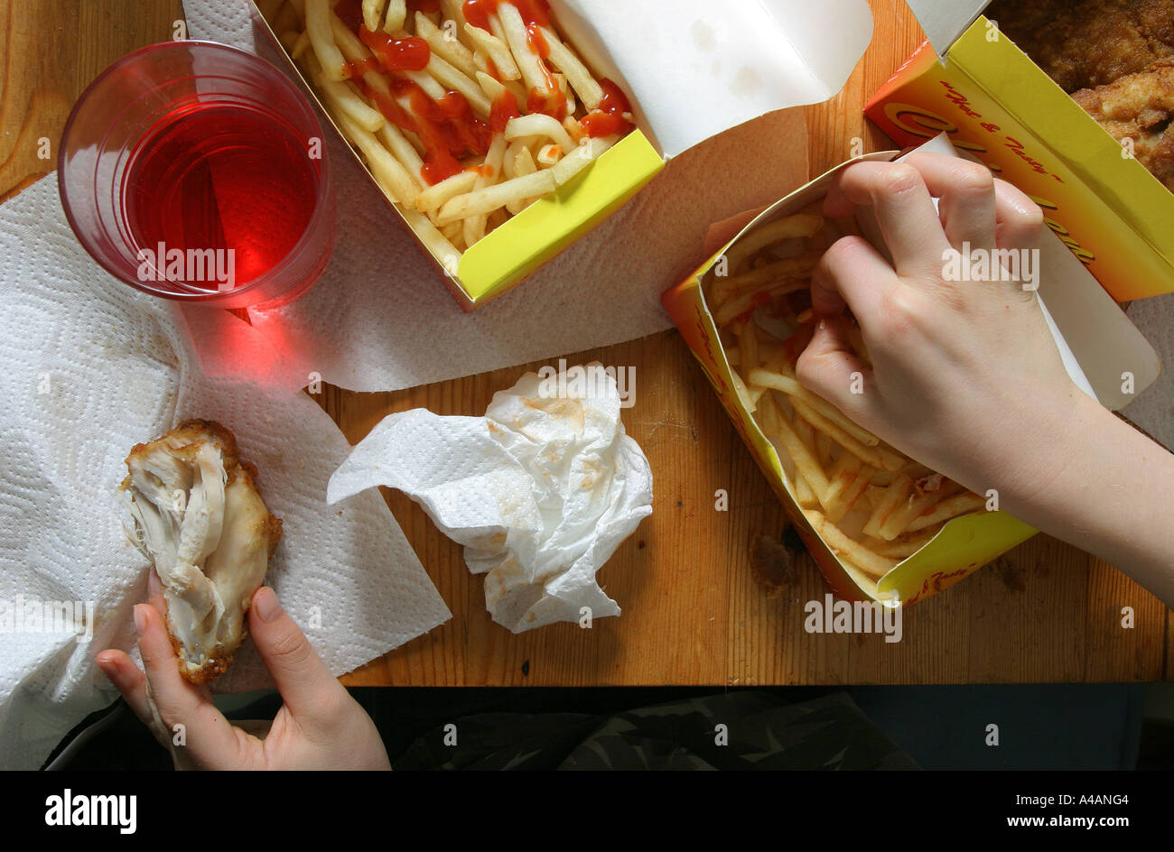 An eight year old boy eating a take away of fried chicken, chips and a