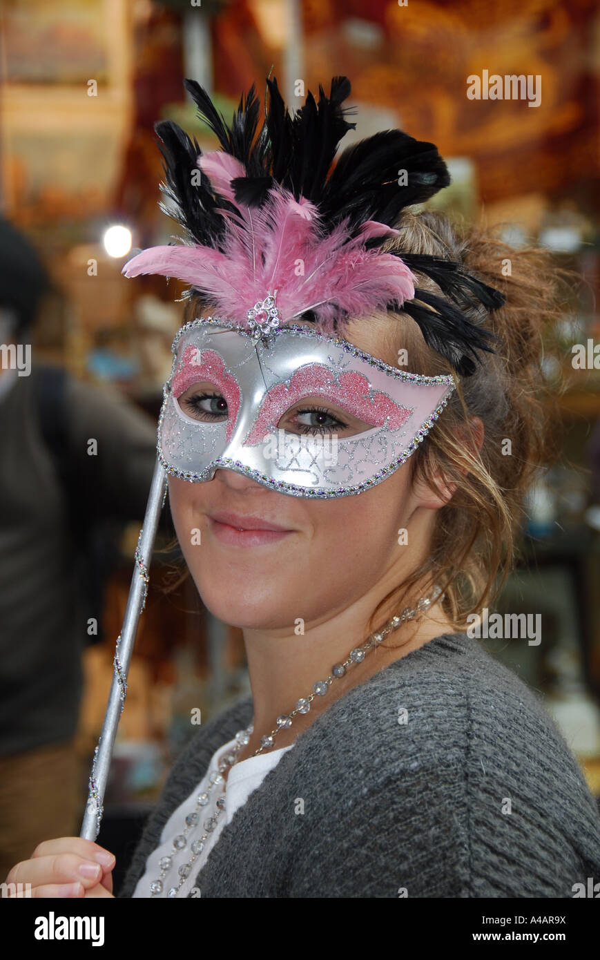 Teenage girl holding a carnival mask to her face in Venice Stock Photo