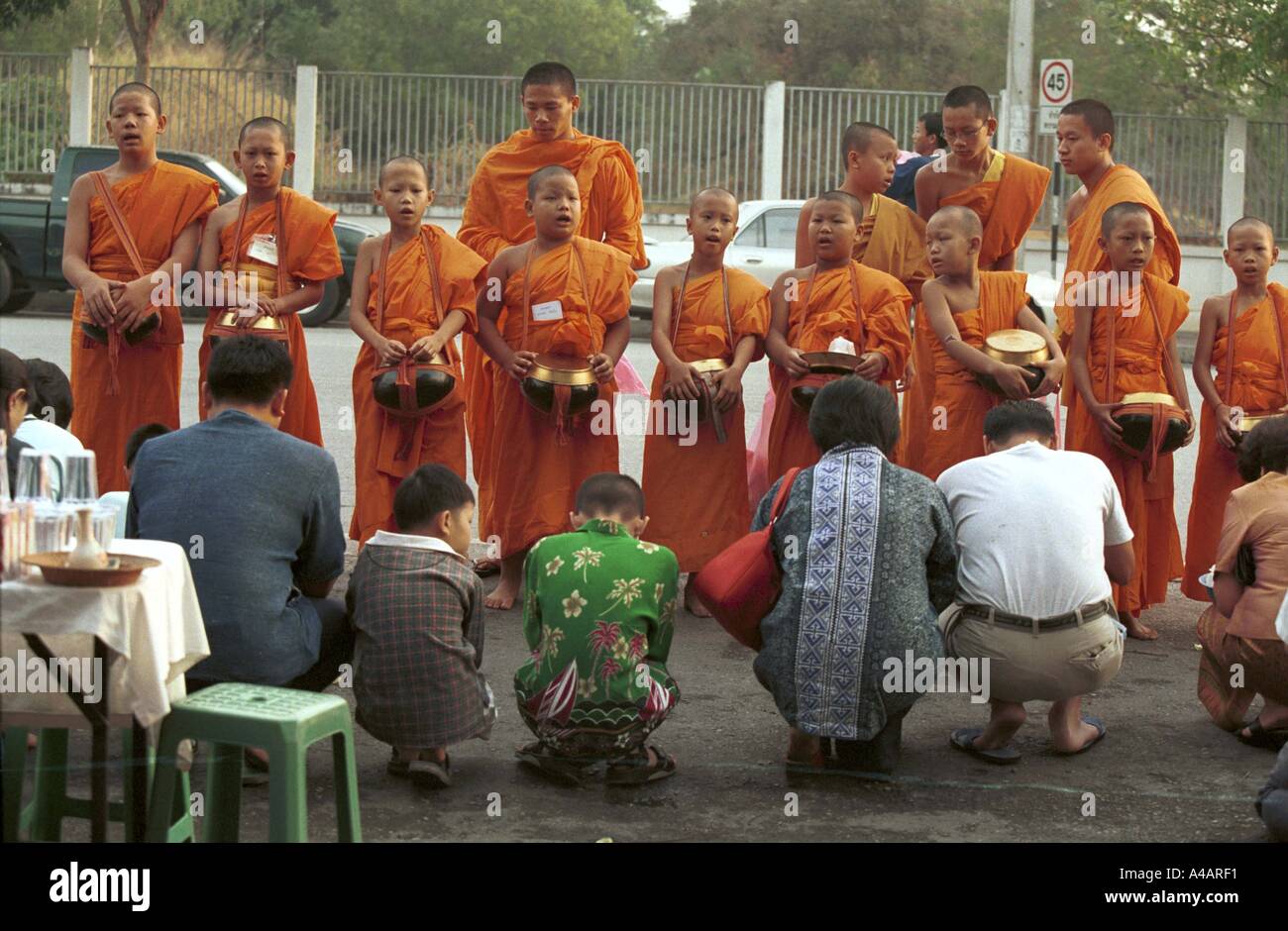 Chang Mai, Thailand  April 2002: In the early morning monks leave their temples to collect food. Giving food is a form of merit. Stock Photo