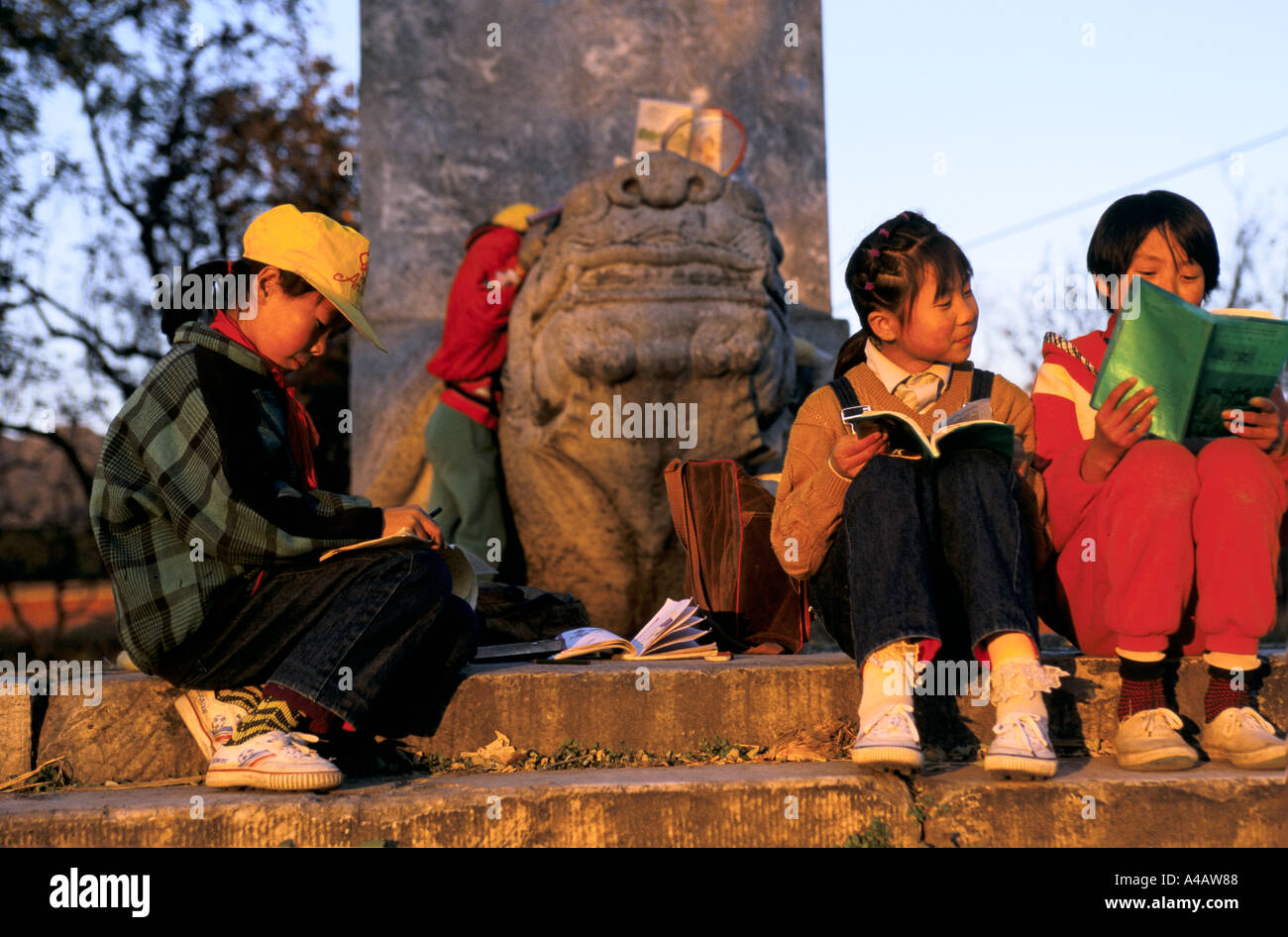 Beijing, China :  school children doing their homework  on the steps at the Ming Tombs at sunset Stock Photo
