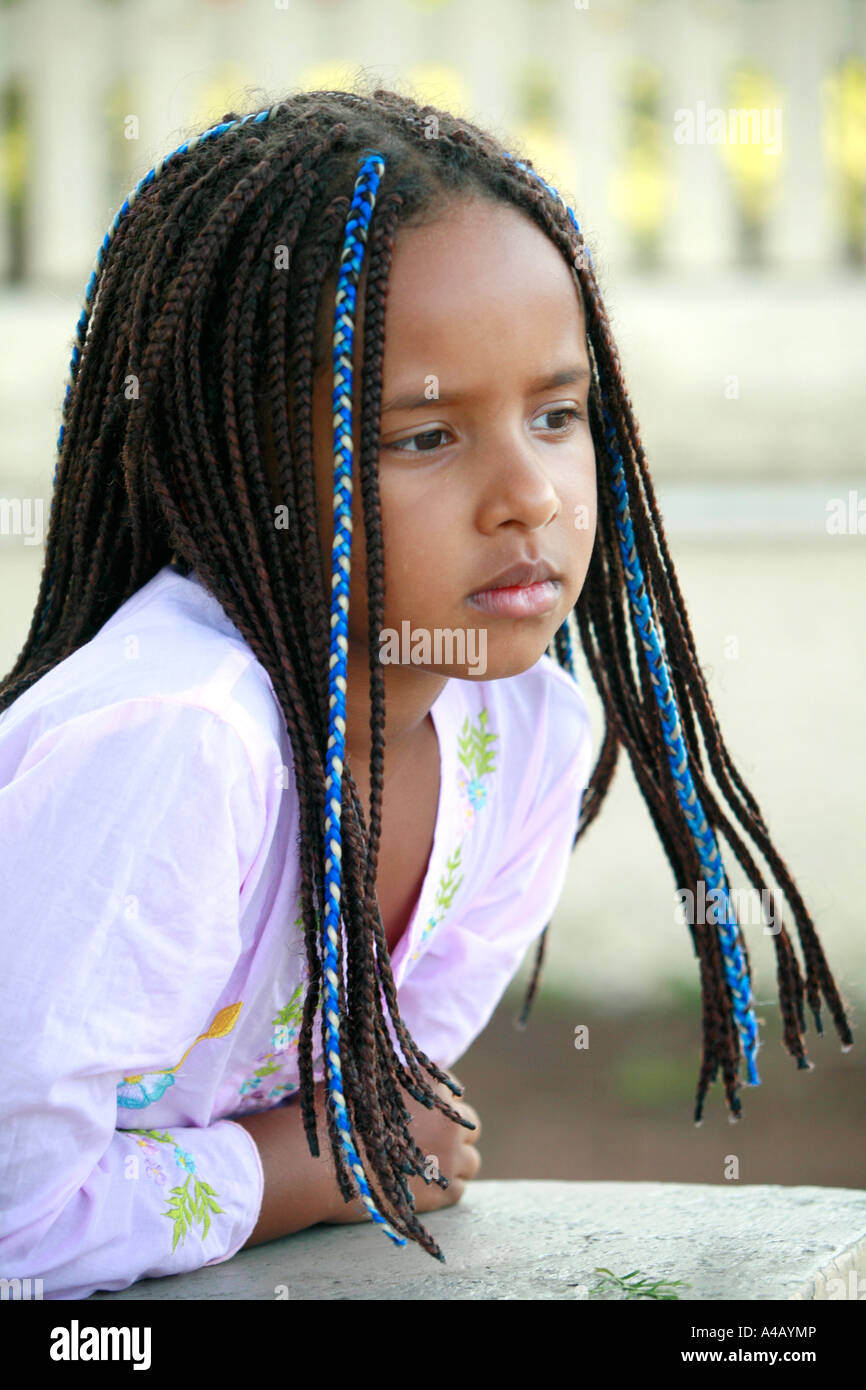 A 6 year old girl of African ancestry with braided hair has a quiet and reflective moment Stock Photo