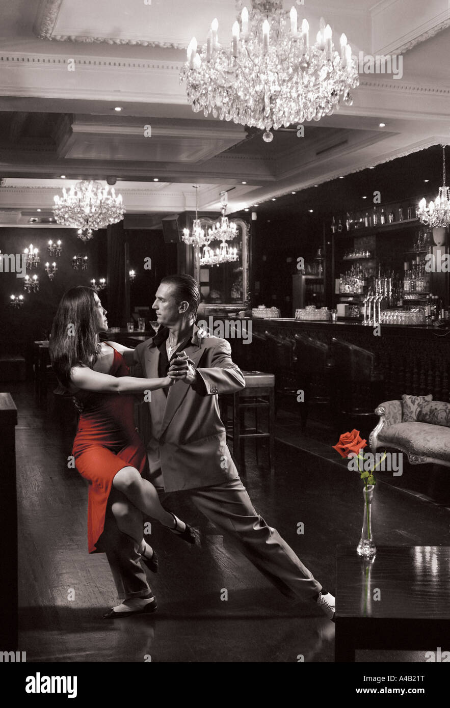 couple dancing tango with crystal chanderliers,red rose red dress Stock Photo
