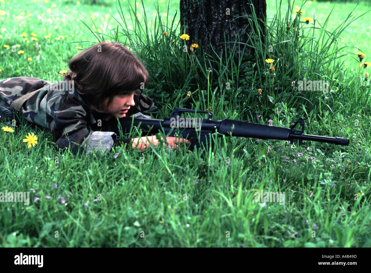 Nine year old girl playing army soldier with toy M16 rifle Stock Photo