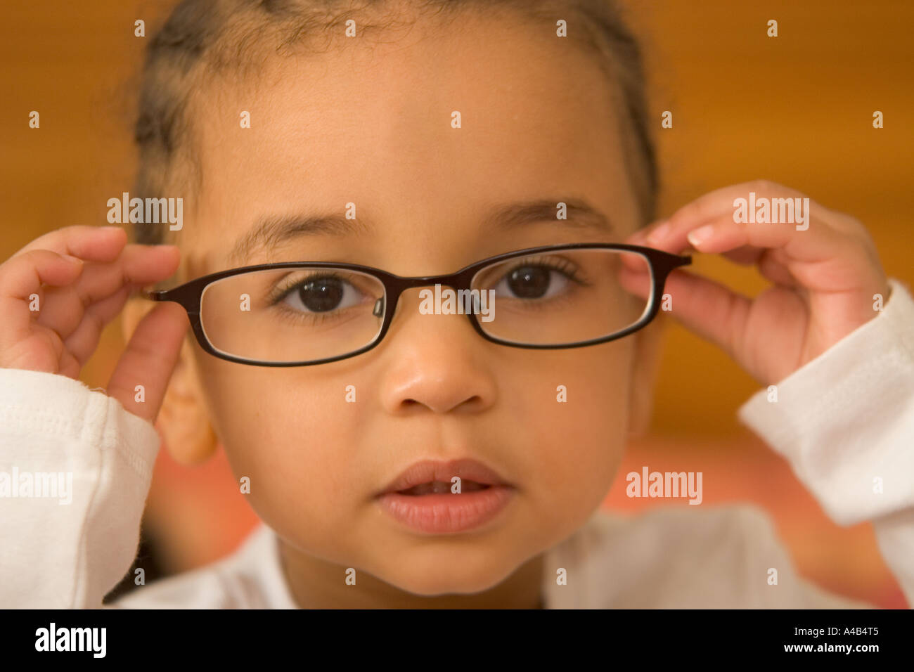 A beautiful young mixed race girl wearing slightly oversized glasses Stock Photo