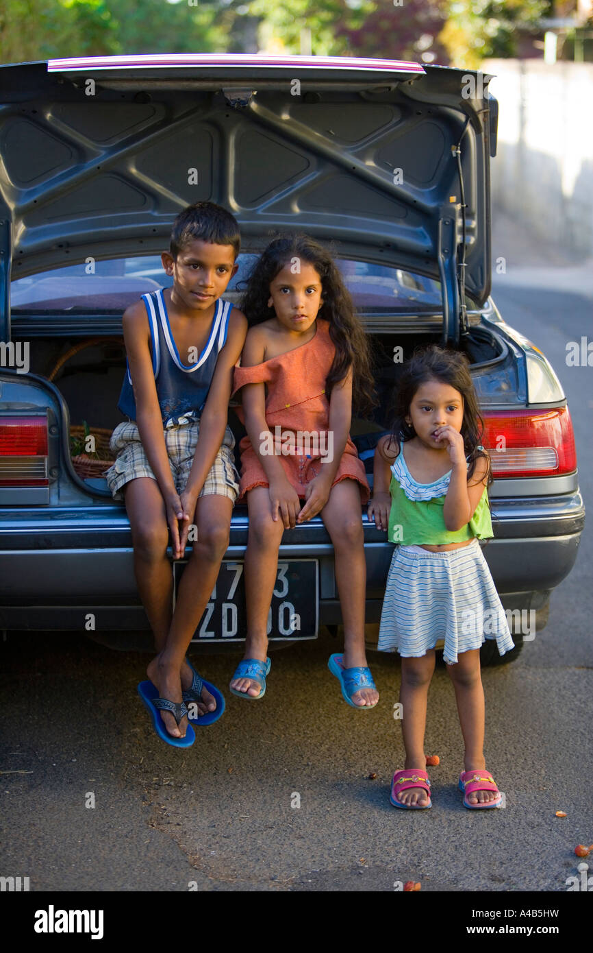 Young Mauritian children resting on car boot in 'Rose Hill', 'Mauritius' Stock Photo