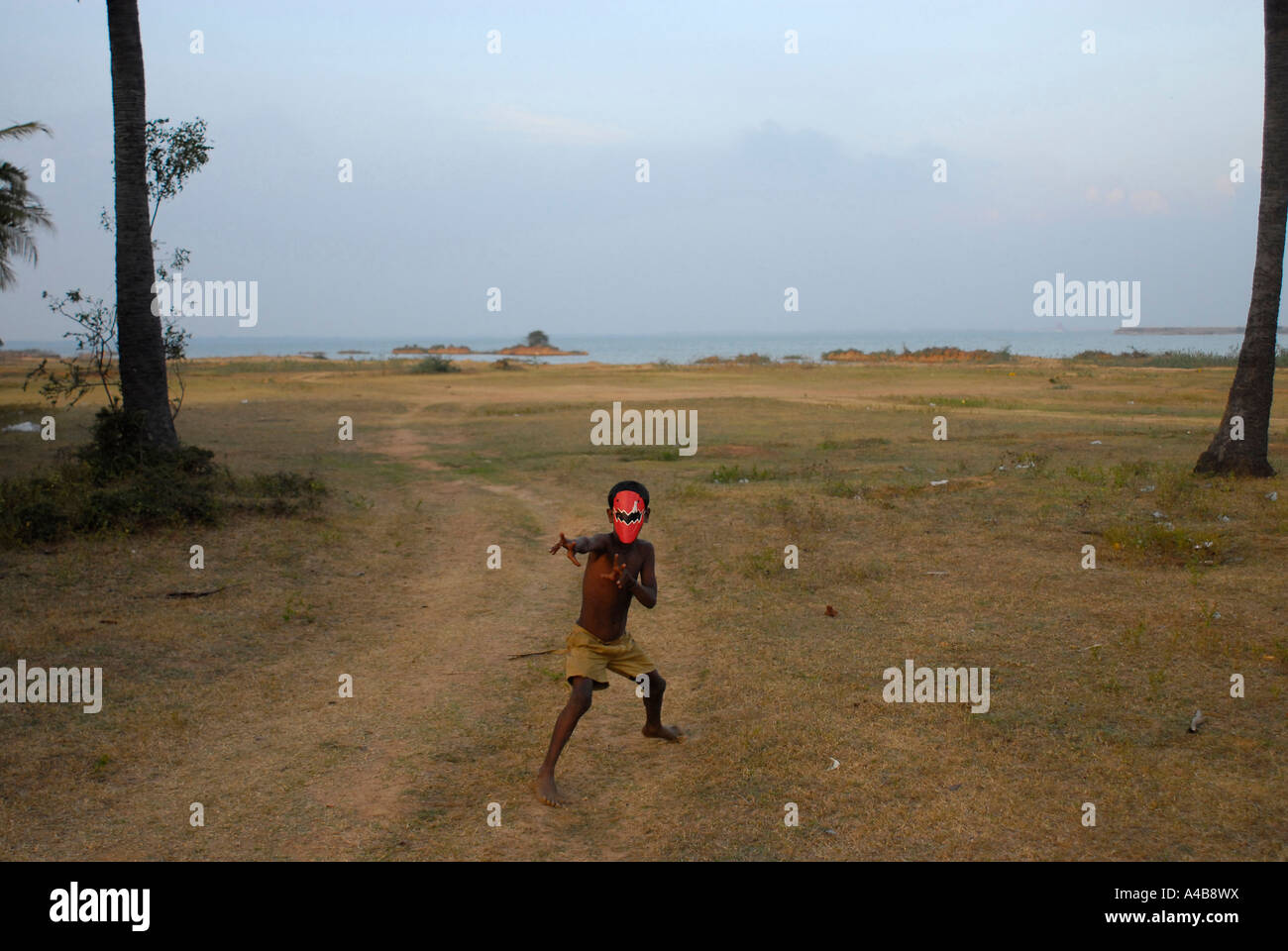 Stock image of an Indian tribal boy with a Spiderman mask on standing alone near Chennai Stock Photo