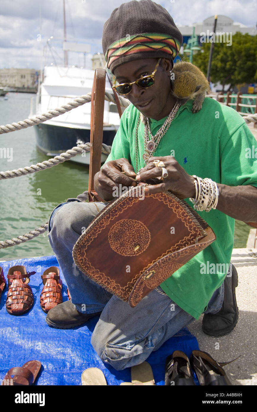 Afro-Caribbean Man sewing hand made bags and selling shoes and bags in Bridgetown Barbados Stock Photo