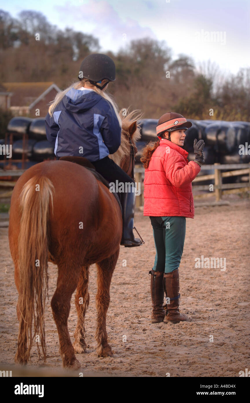 AN INSTRUCTOR TEACHING SCHOOL CHILDREN TO RIDE AT A RIDING SCHOOL