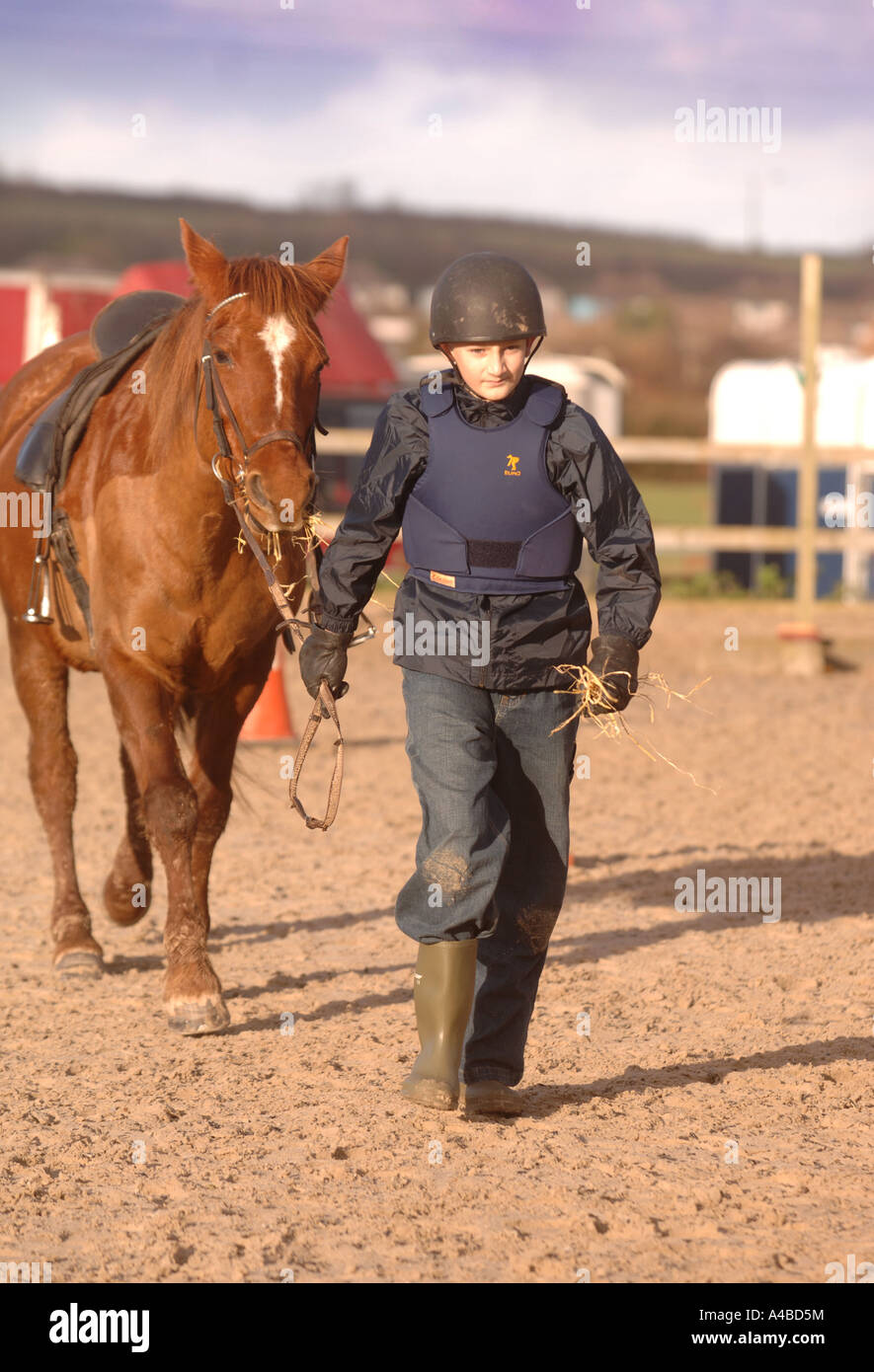 A CHILD LEADING HEIS HORSE WITH HAY AT A RIDING SCHOOL SOMERSET UK Stock Photo