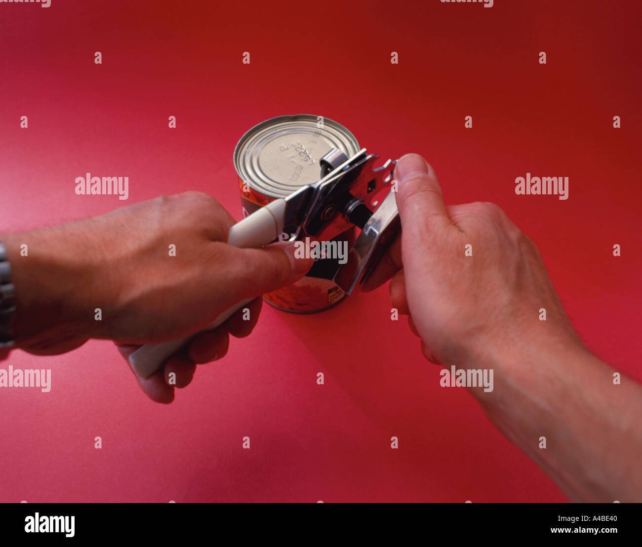 An open can and hand holding a can opener Stock Photo - Alamy