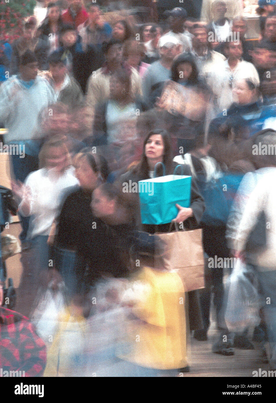 A woman pauses amid a throng of shoppers in a mall Stock Photo