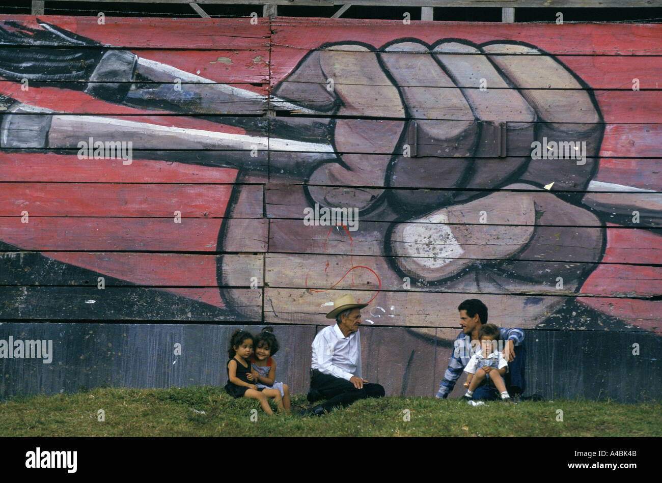 Nicaragua election 1996  - people sit in front of a mural depicting a clenched fist holding artist's  brushes painted on the side of a community centre in Esteli. Stock Photo