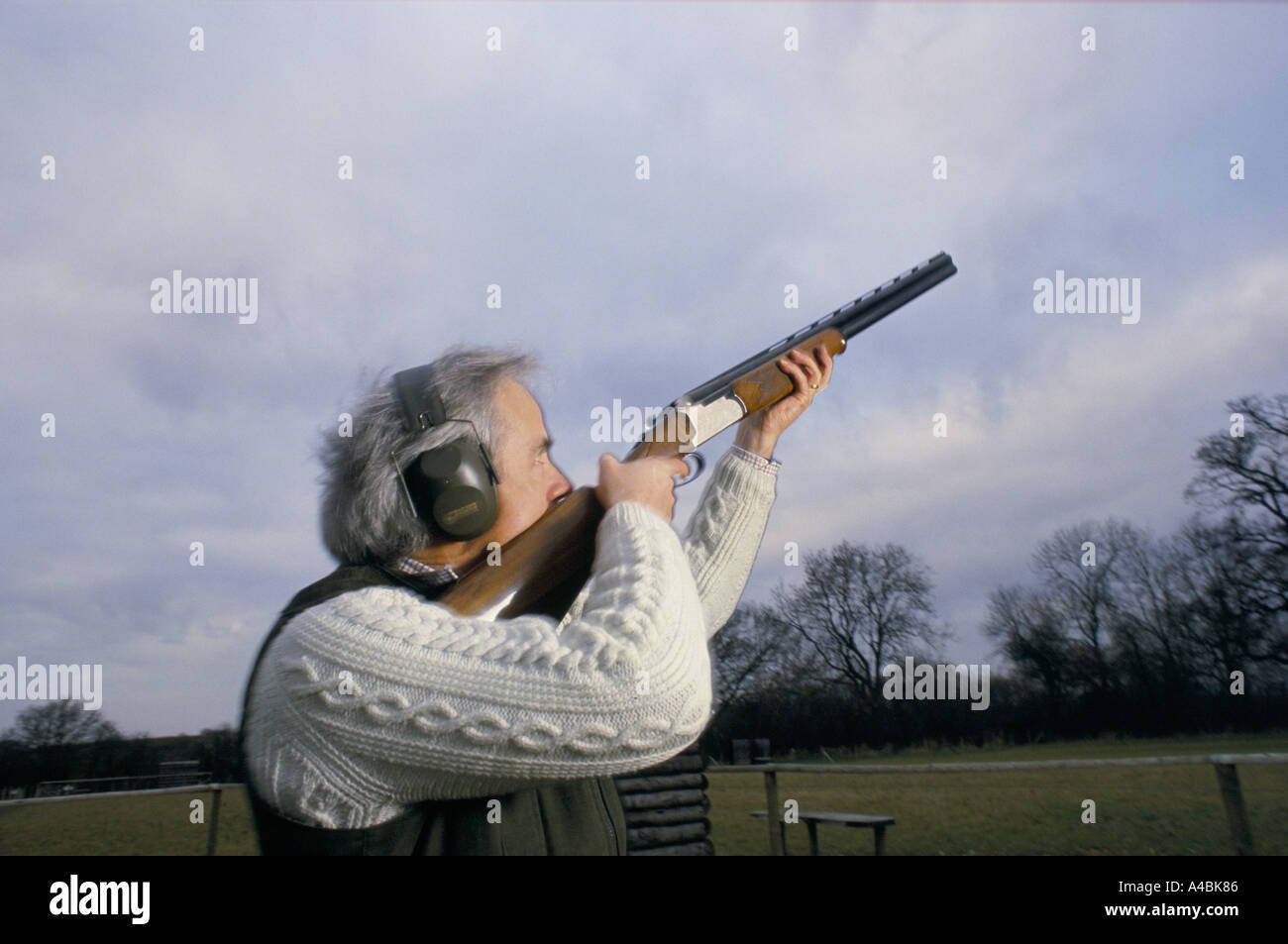 CLAY PIGEON SHOOTING, AIMING SHOTGUN INTO CLEAR BLUE SKY, ENGLAND, 1990 Stock Photo
