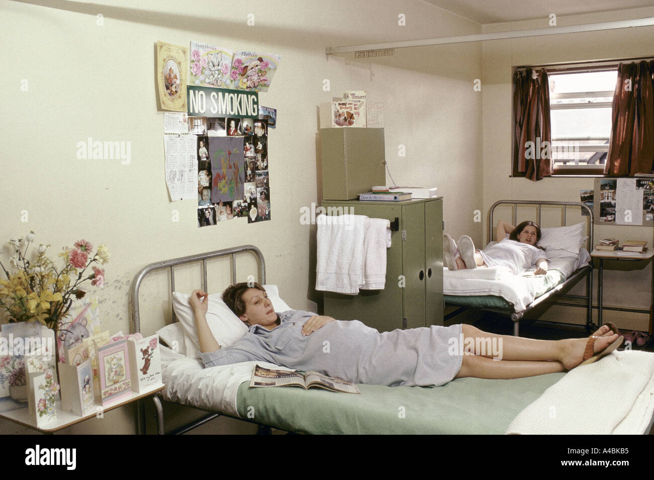 Two pregnant inmates lie on their beds. There are birthday cards, books, magazines and photographs surrounding them.' Stock Photo