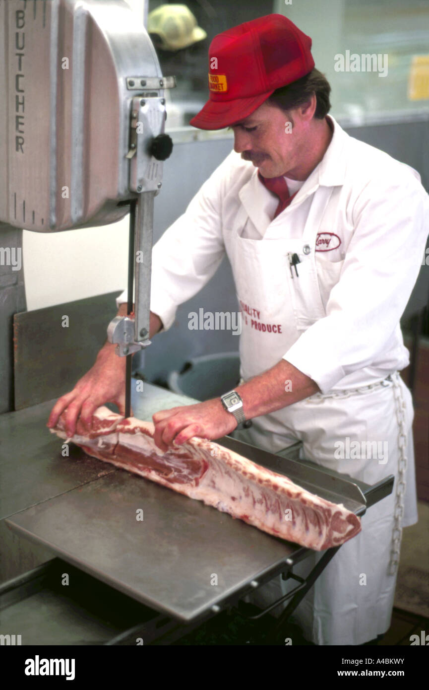 32,298.05300 Man male meat cutter butcher sawing cutting pork or lamb loin meat on a band saw Stock Photo