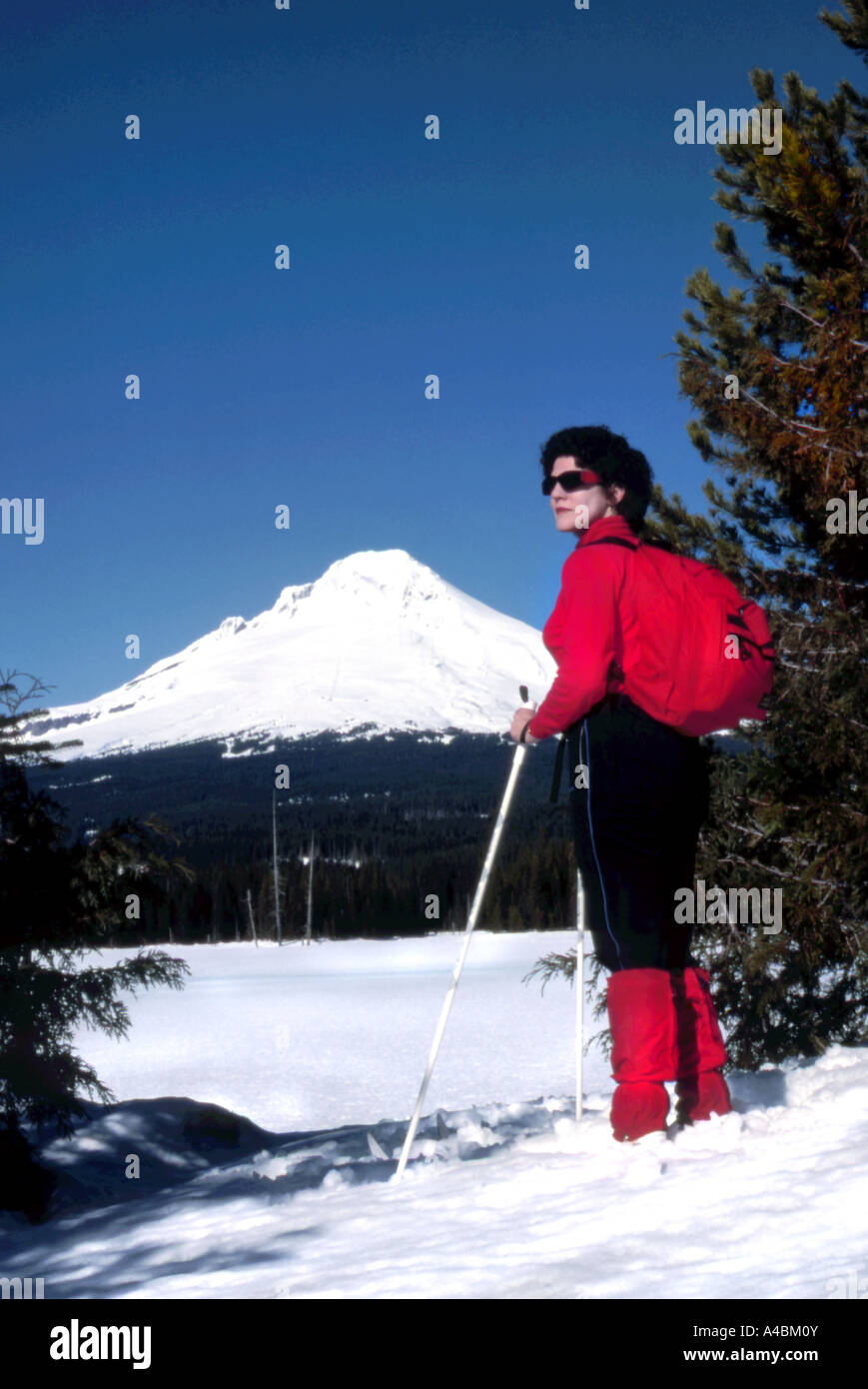 32,928.09200 Cross-country skier woman in red, Mt Hood ski area clear blue sky fresh powder snow snowcapped mountain, magazine copy space, Oregon USA Stock Photo