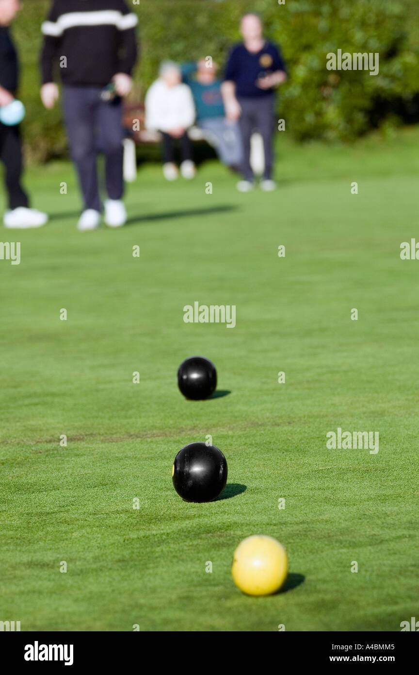 Two bowls and the jack in sharp focus during a crown green bowls match in sunny England bowlers out of focus in the background Stock Photo